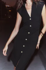 Vestido midi color gris topo, de cuello camisero y escote pico con manga corta. Tiene detalle de drapeado lateral y cierre frontal con botones metálicos.