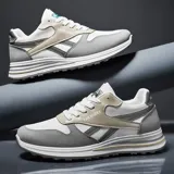 Zapatillas deportivas de estilo retro, color negro con detalles en beige claro y gris. Presentan una capellada de malla y superposiciones de material sintético, cordones negros y una suela gruesa con capas grises.