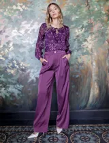 Pantalón palazzo de tiro alto color violeta, de satén. Tiene pretina delantera con pasadores, botón y cierre, pretina trasera elastizada y bolsillos verticales delanteros.