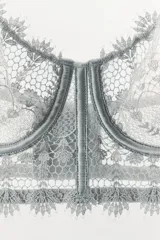 Bralette con aros de escote corazón y tirantes finos ajustables. Detalle de aplicación de tejido combinado en guipur. Varillas interiores que realzan y estilizan la figura. Cierre en espalda con ganchos metálicos.