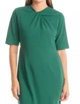 Vestido midi verde de crepe, con cuello a la base, escote entrelazado, mangas cortas y cierre invisible en la espalda con tajo en el ruedo.