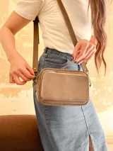 Bandolera color visón, fabricada en cuero con forro de tela. Tiene bolsillo interior y exterior. Entra billetera grande.