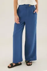 Pantalón de lino azul de corte palazzo con botón decorativo en la cintura.