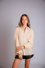 Camisa color beige con bordado inglés, de corte recto, manga larga abullonada con puño y cuello camisero.