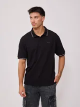 Remera polo negra de corte regular, con cuello y mangas con rayas en contraste blancas y logo bordado en el pecho.