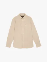 Camisa beige de corte amplio confeccionada en sarga de puro algodón teñido en prenda. Tiene cuello con botones, bolsillo de parche en el pecho y puños redondeados con botón.