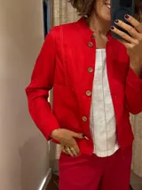 Chaqueta roja de lino y algodón, con cuello mao, corte recto, cierre frontal con botones de madera y bolsillos de parche.