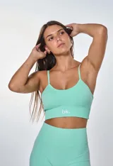 Conjunto deportivo color verde menta, compuesto por un top con breteles finos y logo 'bk.' estampado en el frente, y un short de ciclista de tiro alto.