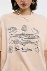 Remera color beige con estampado de sardinas, limones y aceitunas.