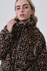 Campera corta de tejido peluche (corderito) con cierre frontal y cuello camisero. Presenta un estampado animal print de cebra o tigre en tonos marrón claro y negro.