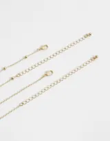 Collar corto dorado de doble cadena, una con cuentas pequeñas y otra con bolitas. Dije redondo esmaltado en blanco con diseño de sol y estrellas.