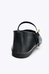 Zapato plano tipo bailarina en piel color negro, con tira sobre el empeine y hebilla metálica ajustable.
