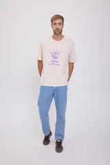Camiseta color crema de manga corta y cuello redondo con estampado de un personaje de caricatura en color violeta y texto "I told you".