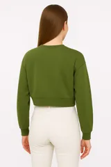 Buzo verde grisáceo corto, con cuello redondo y mangas largas.