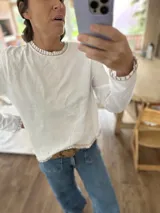 Remera negra de algodón con cuello redondo y bordados blancos en cuello, puños y ruedo. Corte recto.