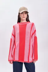 Sweater de punto tejido a rayas verticales rosas y rojas, de corte holgado y cuello redondo.