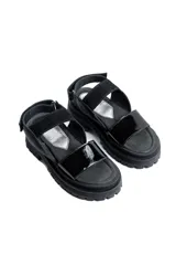 Sandalias negras con plataforma, tiras anchas de cuero sintético y ajuste con velcro en el tobillo.