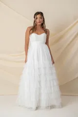 Vestido largo de fiesta color blanco, strapless, con corsé drapeado y falda amplia con volados de tul. Ideal para novias.