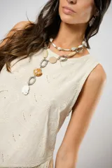 Blusa beige de lino bordado, sin mangas y con terminación en flecos.