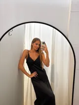 Vestido largo negro de seda, con escote en V adornado con encaje delicado y tirantes finos.