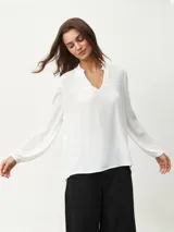 Blusa blanca de manga larga con escote en V y textura arrugada.