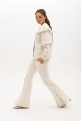 Pantalón de gabardina elastizada color crudo, de corte acampanado con aberturas laterales en el ruedo.