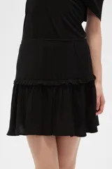 Minifalda negra con cintura alta y volados en el ruedo.