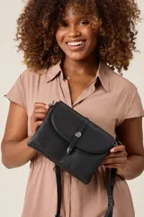 Bandolera negra de ecocuero con correa ajustable y solapa con cierre de botón metálico.