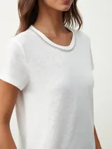 Remera blanca de algodón con cuello redondo y detalle de strass plateado.