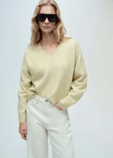 Sweater color crema con cuello en V, de tejido de punto y manga larga.