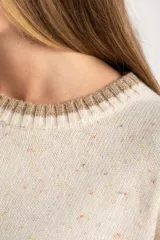 Sweater de lana color crema con efecto tweed, de calce oversize y cuello redondo. Presenta bloques de color en la parte inferior, puños y laterales de las mangas en tono beige con textura acanalada y detalles brillantes.
