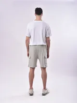 Bermuda color gris con cintura elástica ajustable con cordón, bolsillos laterales y un bolsillo tipo cargo en la pierna izquierda.