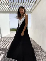 Vestido largo negro con escote en V y breteles finos. Presenta un aplique triangular de lentejuelas plateadas en la parte superior.