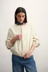 Chaqueta bomber negra con cierre frontal dorado y mangas largas con puños elásticos.