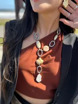 Collar largo con cadena plateada y colgantes de piedras reconstituidas, cerámica, acrílico y una concha marina.