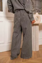 Pantalón denim gris con efecto lavado y detalles de pedrería en el frente, de corte amplio.