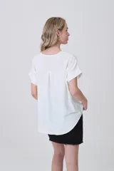 Blusa holgada de poliéster color blanco, con escote en V profundo y pinzas frontales que generan caída. Mangas cortas.