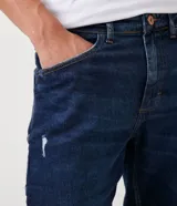 Pantalón de jean azul oscuro, corte slim, con bolsillos delanteros y traseros.
