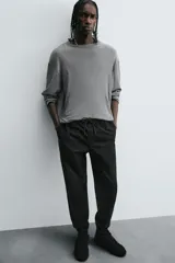 Pantalón jogger negro de corte slim fit, confeccionado en tejido de algodón con cintura elástica ajustable con cordón, bolsillos frontales y traseros de vivo, y bajo con puño elástico.