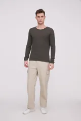 Sweater de algodón color verde oscuro, de manga larga y cuello redondo a la base. Presenta un tejido texturizado de punto fino.