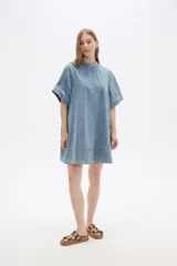 Vestido corto de jean celeste, de corte holgado, manga corta y cuello redondo.