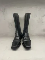 Bota de caña media color negro con puntera cuadrada y tres tiras horizontales con hebillas.