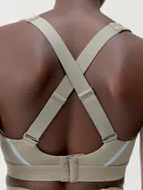 Top deportivo negro de alta sujeción con tirantes regulables cruzados y cierre ajustable en la espalda. Tejido Shape_Tech con tecnología performance y cinta reflectante.