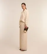 Pantalón recto de chiffon color crema con cintura elástica, lazo ajustable y textura de encaje.