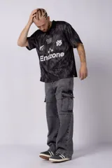 Camiseta de fútbol negra con estampado abstracto en gris, cuello tipo chomba y logos estampados en el frente.