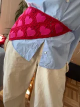 Pañuelo triangular de crochet con diseño de corazones en rojo y rosado.