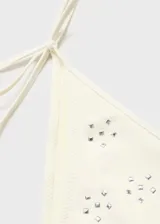 Traje de baño de dos piezas color blanco, con apliques metálicos y cierre de lazos ajustables.