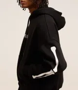 Buzo negro de fleece con felpa, corte boxy, capucha con cordón ajustable, manga larga, estampa lettering frontal, bolsillo canguro, patch de esqueleto en la manga y puños ajustados.