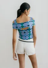 Top de jersey con estampado abstracto en tonos celeste, azul y negro. Diseño con hombros descubiertos y corte cruzado en el frente.