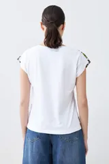 Remera blanca de algodón con escote en V y estampado floral en el frente y los hombros.
